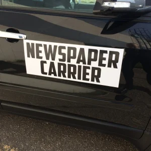 car magnet printed with the words newspaper carrier on side of black car