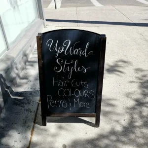 a chalkboard with white writing that advertises haircuts