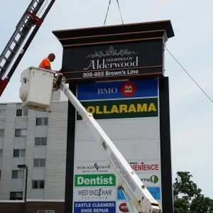 man installing sign on pylon using a bucket truck