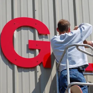 Sign installer installing sign on side of building