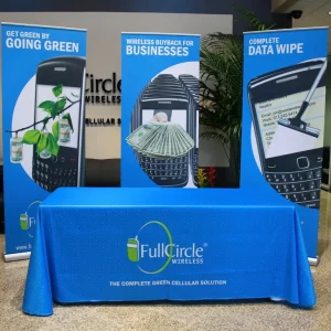 Three custom print pull up banners behind a table with a custom print table cloth draped over it for a trade show