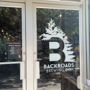 white cut vinyl logo and lettering applied to the glass door of the entrance to a brewery